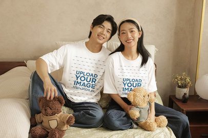 Oversized T-Shirt Mockup of a Smiling Couple Posing in a Bed With Cozy Teddy Bears