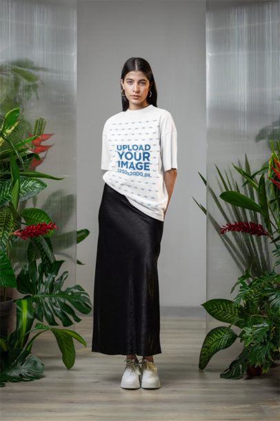 Oversized T-Shirt Mockup Featuring a Serious Woman Posing With Plants