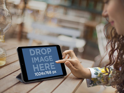 Mockup of a Pretty Girl Sitting on Outdoor Patio Using a Black iPad