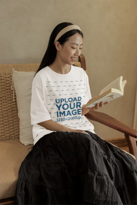 Oversized T-Shirt Mockup of a Happy Woman Reading in a Cozy Space