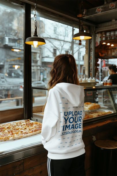 Back-View Hoodie Mockup of an AI-Generated Woman in a Pizza Restaurant