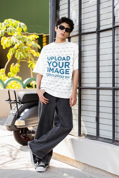Oversized T-Shirt Mockup Featuring a Serious Man Leaning on a Window in the Street m55818