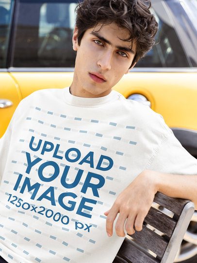 Oversized Tee Mockup of a Man Sitting on a Street Bench and Posing With a Serious Look m55820
