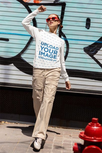 Comfort Colors Long-Sleeve Tee Mockup Featuring a Woman Posing Against a Graffiti Wall in the Street m55809