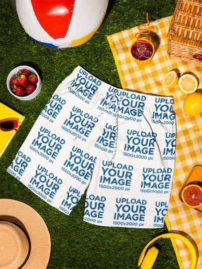 Summer Mockup Featuring Swim Shorts Lying on the Grass With Fruits and a Fresh Drink