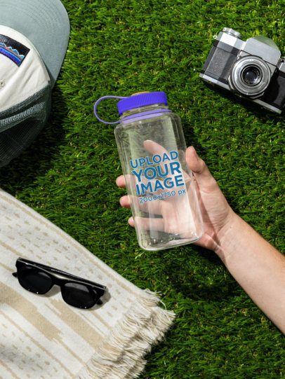 Mockup of a Man's Hand Grabbing a Nalgene Water Bottle While Lying on the Grass m55032