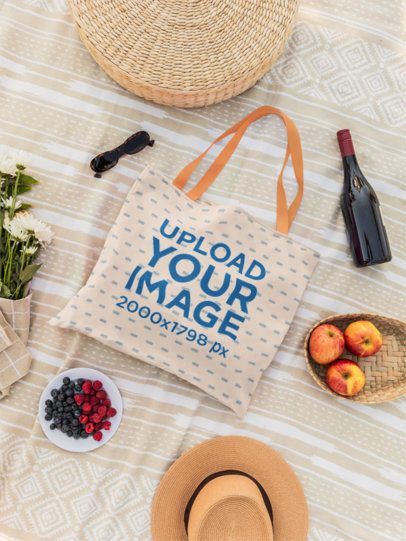 Mockup of a Sublimated Tote Bag Lying on a Table Cloth With Picnic Stuff m56504