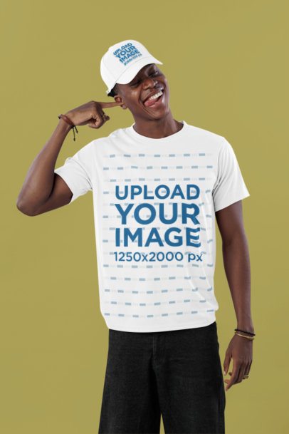T-Shirt Mockup of a Man Wearing a Dad Hat in a Studio While Making a Funny Pose