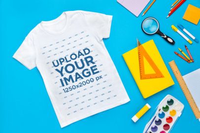 Mockup of a Bella Canvas T-Shirt Lying on a Surface With School Stuff m56712