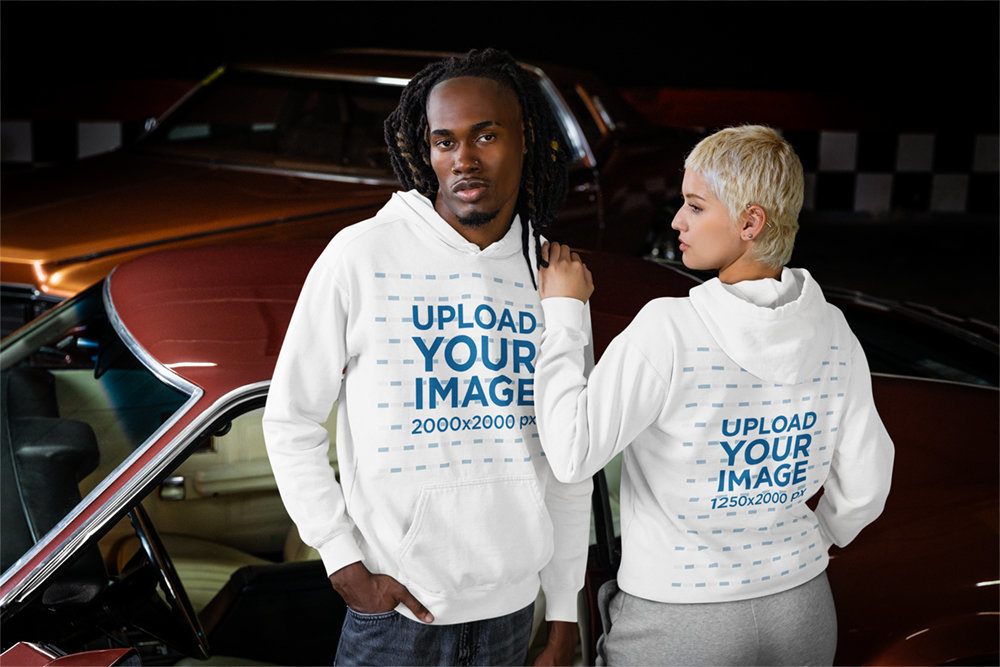 Comfort Colors Mockup Featuring a Man and a Woman Wearing Hoodies and Posing Against a Classic Car