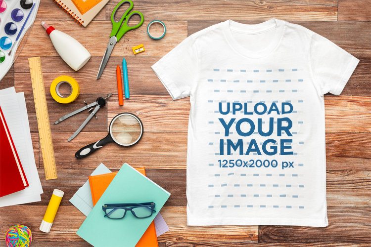 Mockup of a Bella Canvas Round-Neck Tee Placed on a Wooden Surface With School Stuff