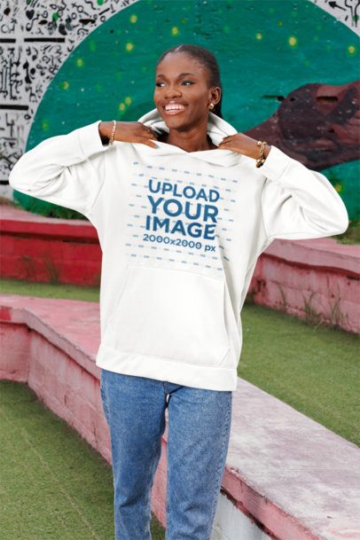 Hoodie Mockup Featuring a Woman With a Joyful Expression Posing in a Park