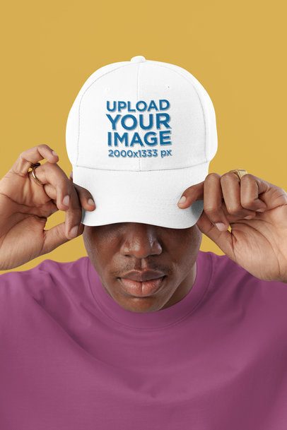 Mockup of a Man Putting On an Embroidered Dad Hat in a Studio