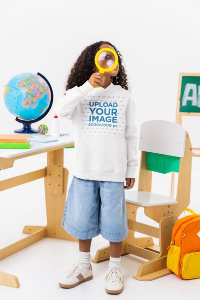 Hoodie Mockup of Curly-Haired Girl Posing With a Hand Lens in a School Setting