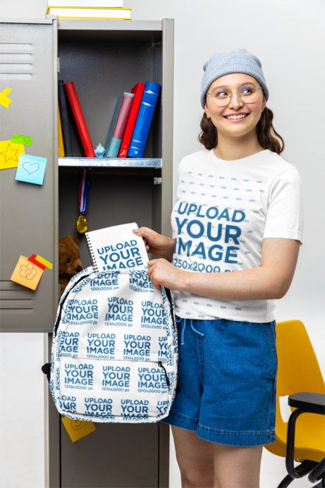 Bella Canvas T-Shirt Mockup of a Young Smiling Woman Putting a Notebook Inside a Backpack