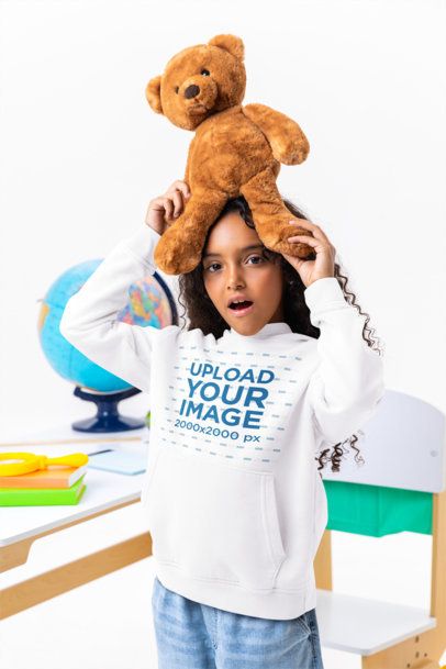 Pullover Hoodie Mockup of a Surprised Girl Holding a Teddy Bear in a Classroom Setting m56984