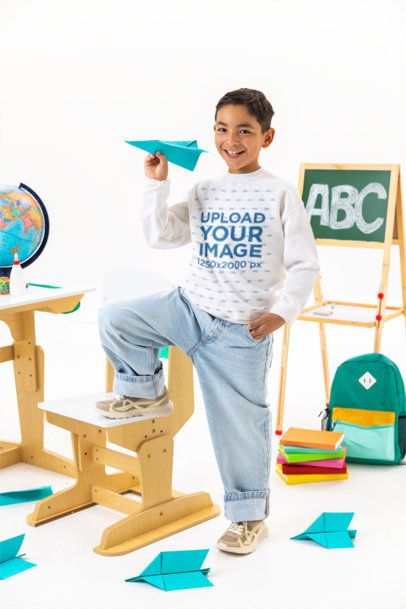 Gildan Sweatshirt Mockup of a Happy Boy With a Paper Airplane in a Classroom Setting