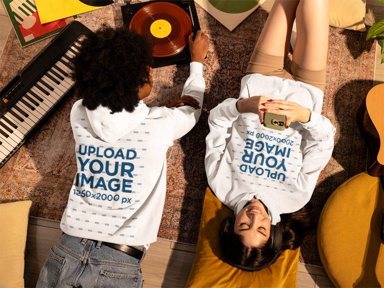 Comfort Colors Hoodie Mockup Featuring a Couple Relaxing on the Floor in a Comfy Spot