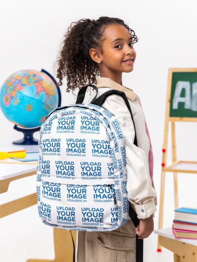 Mockup of a Happy Girl Carrying a Sublimated Backpack in a Classroom Set