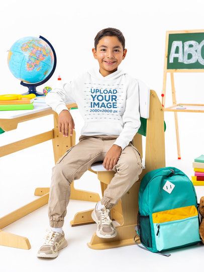 Pullover Hoodie Mockup of a Smiling Boy Sitting in a Wooden School Chair m56980