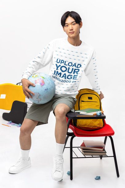 Comfort Colors Sweatshirt Mockup Featuring a Young Man Holding a Globe in a School Setting