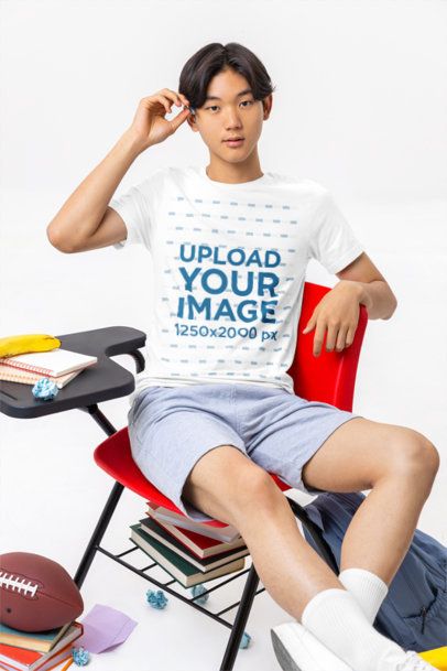 Bella Canvas T-Shirt Mockup Featuring a Young Man Student Sitting on a Chair in a School Classroom
