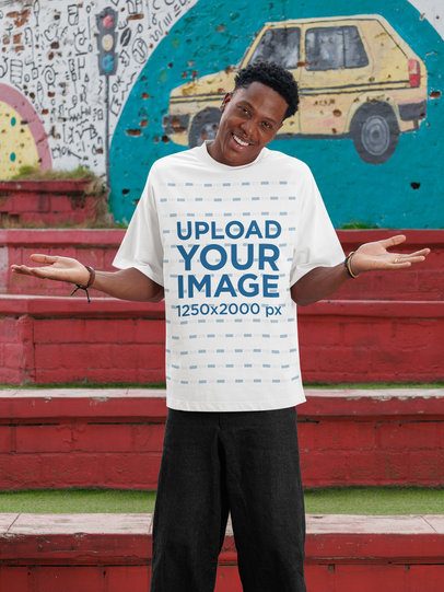 Oversized T-Shirt Mockup of a Smiling Man Standing in the Street With a Cheerful Expression