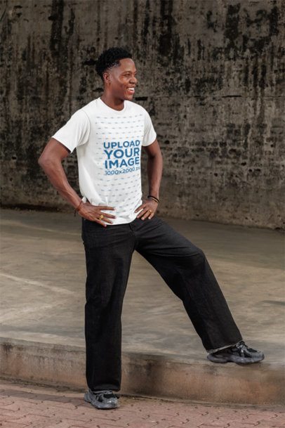 Round-Neck T-Shirt Mockup of a Happy Man Posing on a Sidewalk With His Hands on His Waist