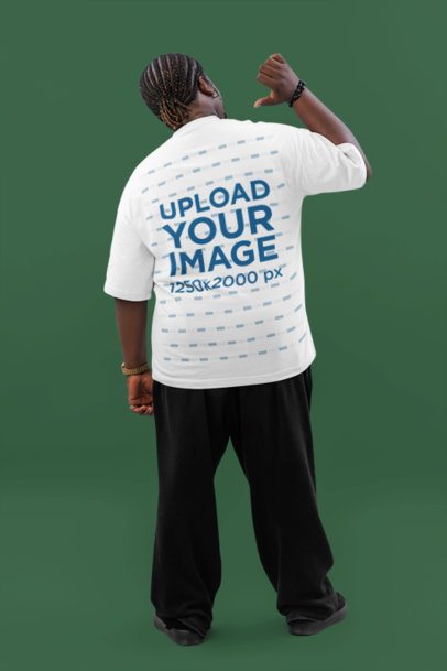Back-View Mockup of a Man Pointing at His Oversized T-Shirt in a Studio