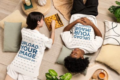 Oversized T-Shirt Mockup of a Man and a Woman Lying on the Floor and Playing Chess
