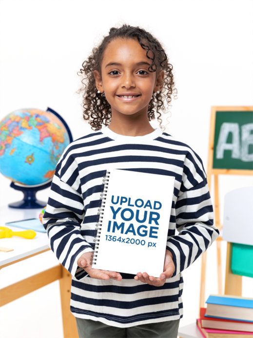 Mockup of a Happy Girl Holding a Spiral Notebook in a Studio