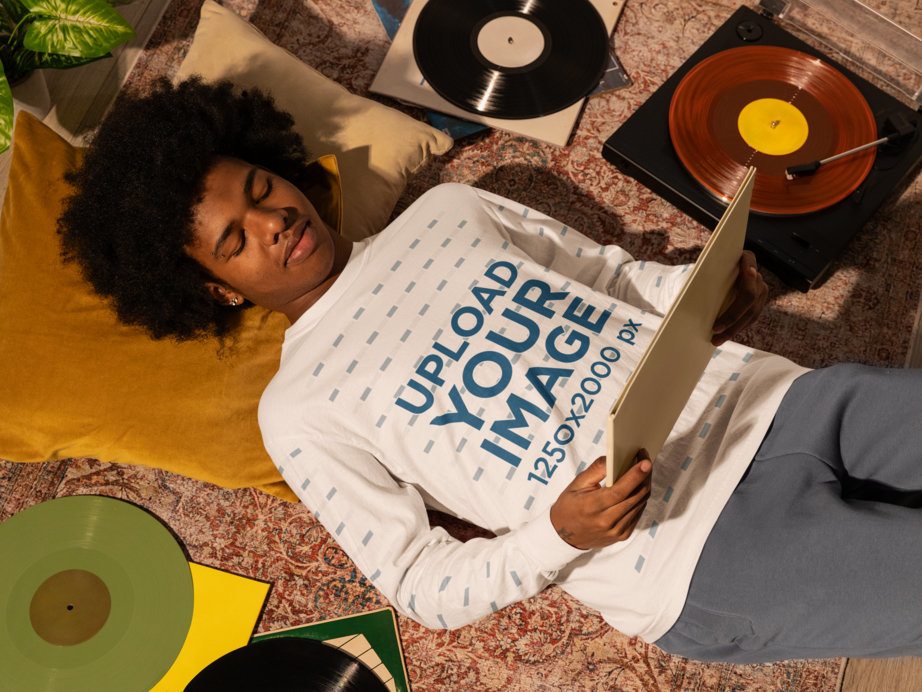 Comfort Colors Mockup of a Man in a Long-Sleeve Tee Resting on the Floor and Holding a Music Album