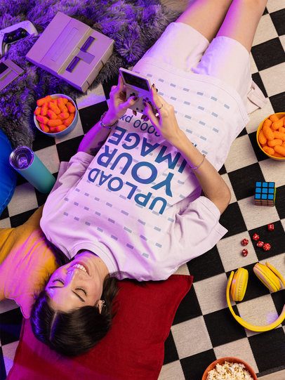 Oversized T-Shirt Mockup of a Smiling Woman Playing With a Gaming Console m56633