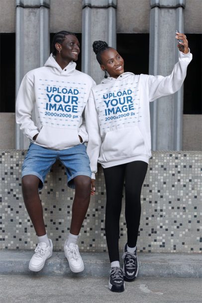 Pullover Hoodie Mockup of a Happy Man and Woman Taking a Selfie on the Sidewalk
