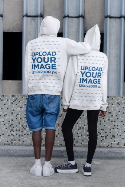 Back-View Hoodie Mockup Featuring a Man and a Woman Posing on the Sidewalk