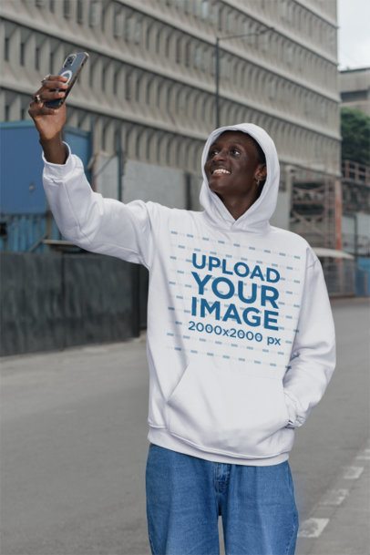 Pullover Hoodie Mockup Featuring a Happy Man Taking a Selfie While Standing in the Street