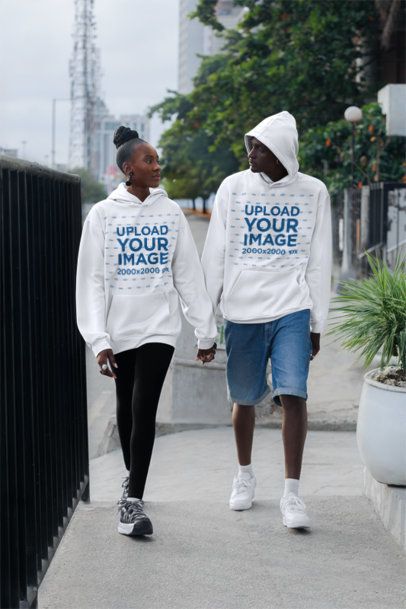 Pullover Hoodie Mockup Featuring a Couple Walking Hand-in-Hand in the Street