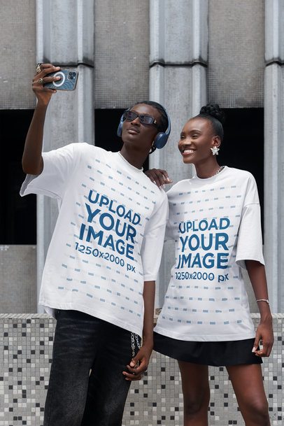 Oversized T-Shirt Mockup Featuring a Man Taking a Selfie With a Smiling Woman