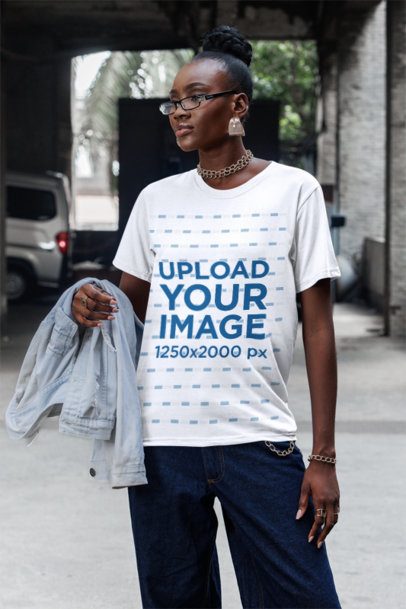 Round-Neck T-Shirt Mockup Featuring a Woman With Glasses Standing on the Sidewalk
