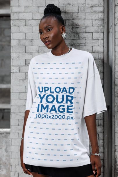 Oversized T-Shirt Mockup of a Woman Posing With a Serious Look Against a Brick Wall