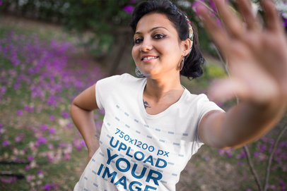 T-Shirt Mockup Featuring a Woman Reaching for the Camera while Posing