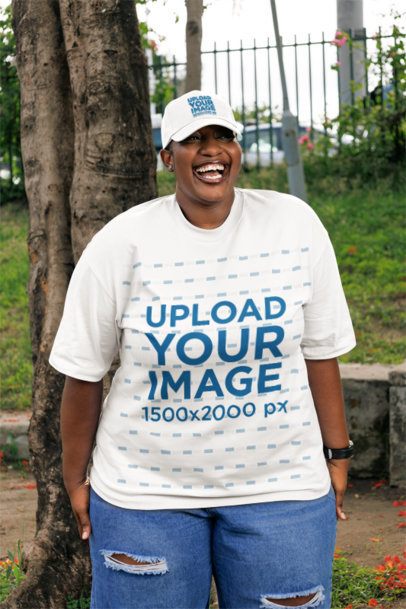 Oversized T-Shirt Mockup of a Joyful Woman in a Dad Hat Laughing in the Park