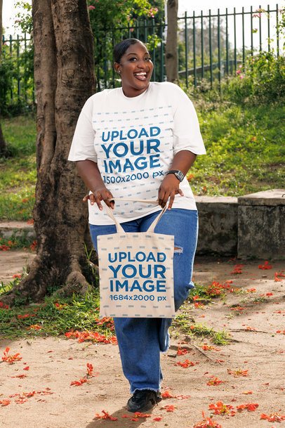 Oversized T-Shirt Mockup Featuring a Cheerful Woman Holding a Sublimated Tote Bag