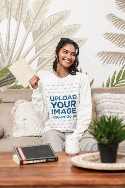 Sweatshirt Mockup Featuring a Cheerful Woman Sitting on a Cozy Couch in a Nice Living Room m55376