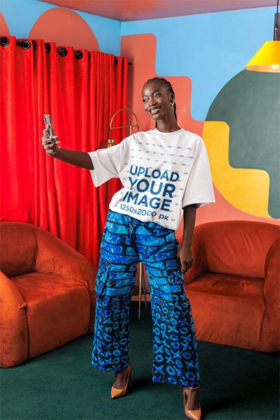 Oversized T-Shirt Mockup Featuring a Woman in a Colorful Room Taking a Selfie