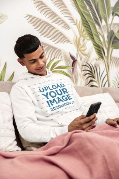 Pullover Hoodie Mockup Featuring a Smiling Man Checking His Phone in a Cozy Room m55444
