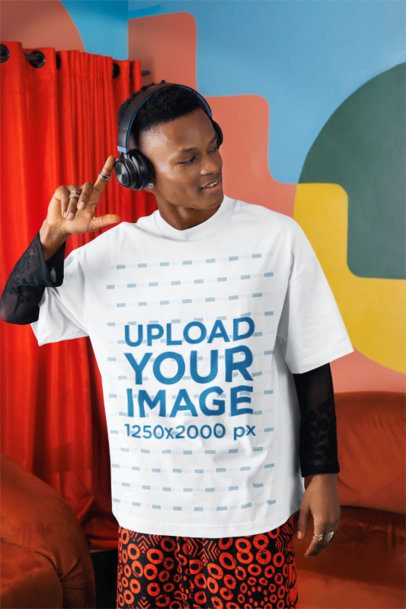 Oversized T-Shirt Mockup Featuring a Man Listening to Music in a Colorful Living Room