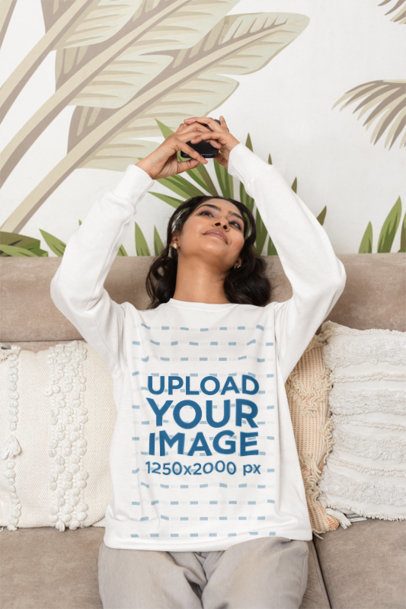 Sweatshirt Mockup Featuring a Smiling Woman Looking at Her Phone on the Couch m55377