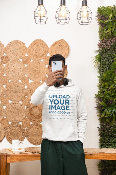 Hoodie Mockup Featuring a Man Standing in a Cozy Room While Taking a Selfie m55435