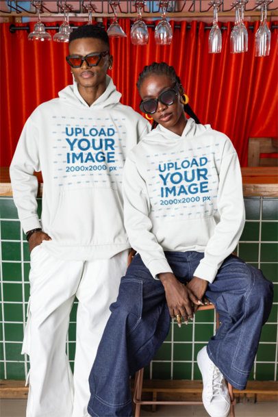 Pullover Hoodie Mockup Featuring a Cool Couple With Sunglasses Posing in a Bar